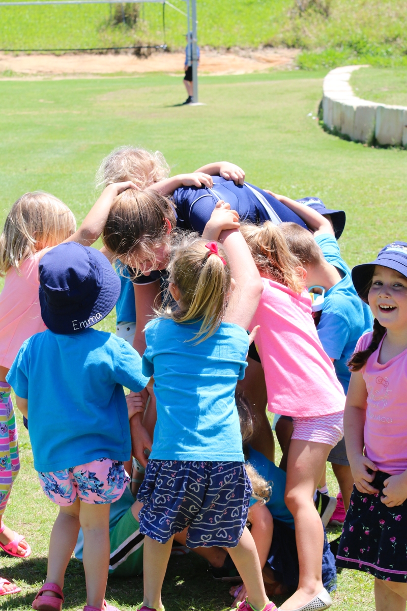 Preschool Kindergarten students hugging teacher. Sunshine Coast
